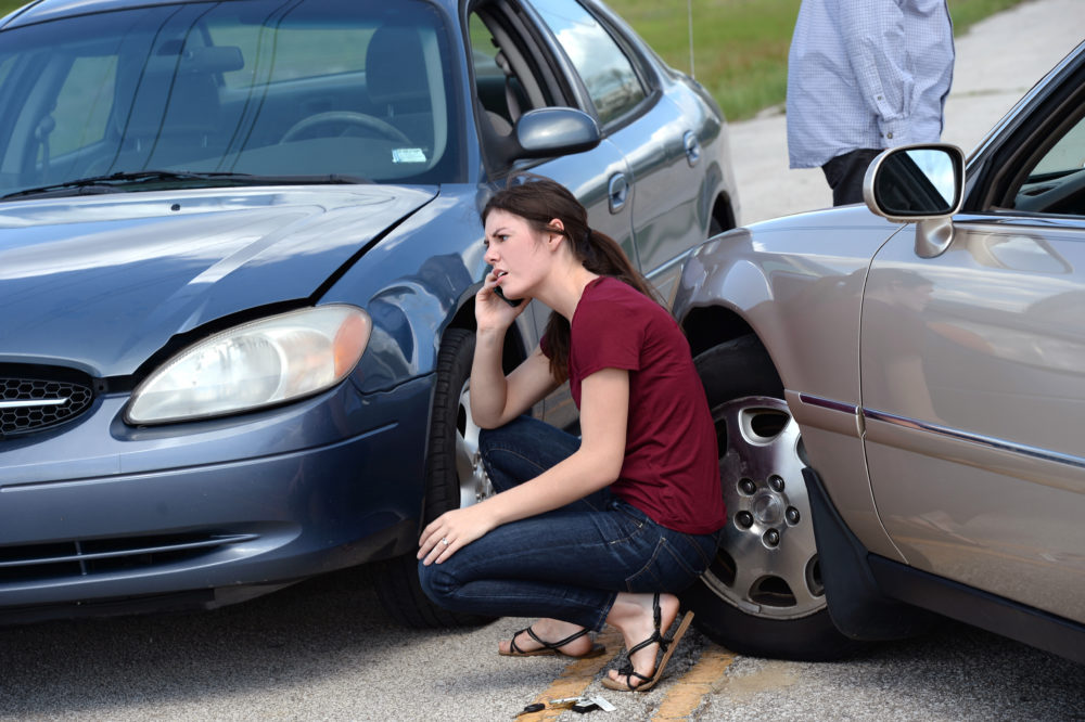 Young woman making phone call after accident. Wade Insurance Agency